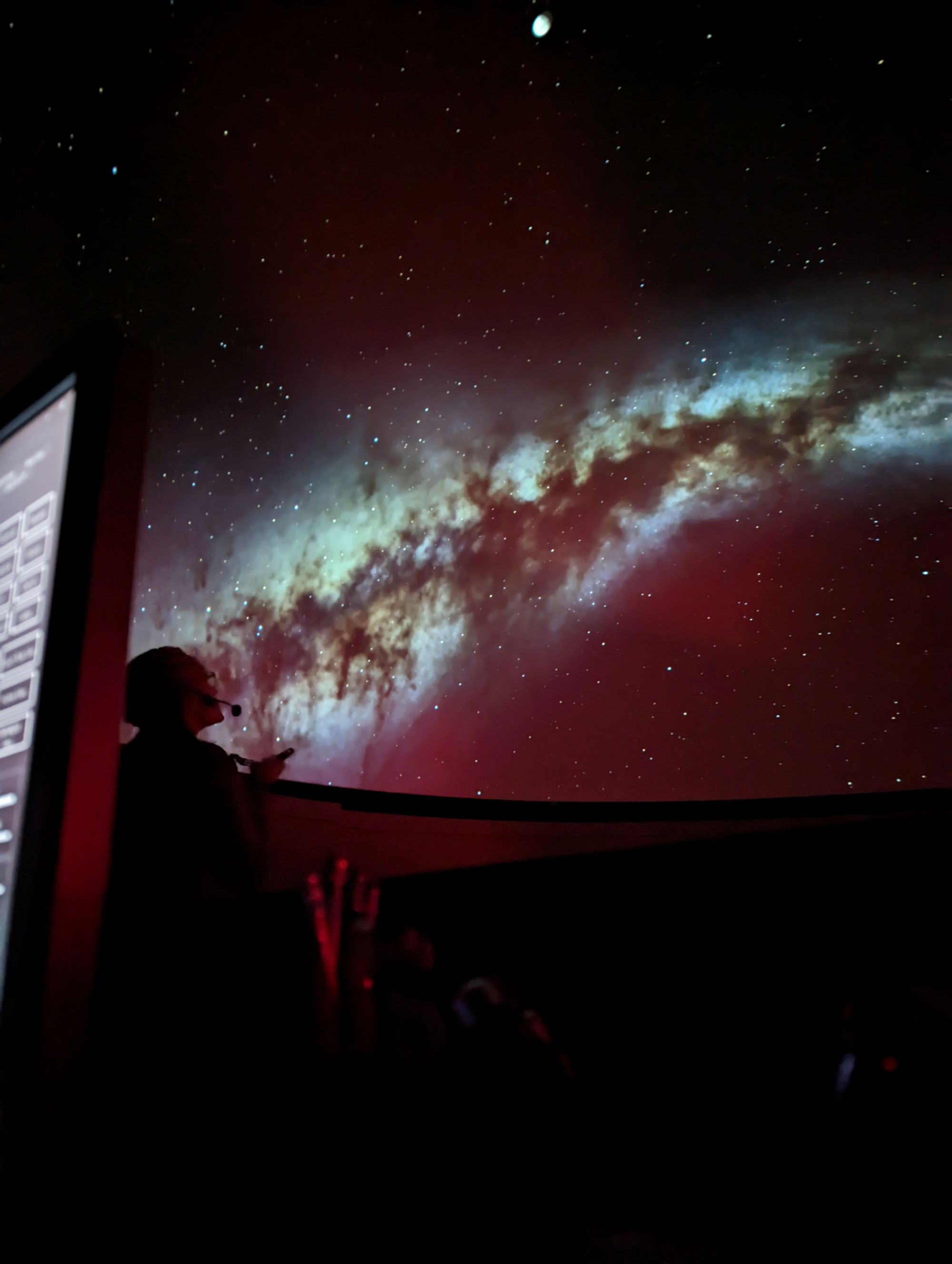 image of person with a laser pointer in silhouette in front of a projection of the Milky Way galaxy